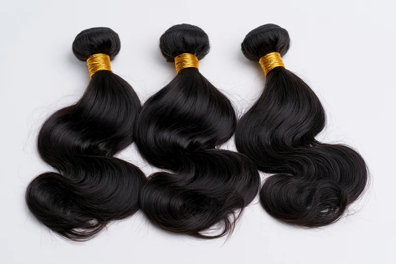 Three bundles of black body wave hair extensions laid flat on white background