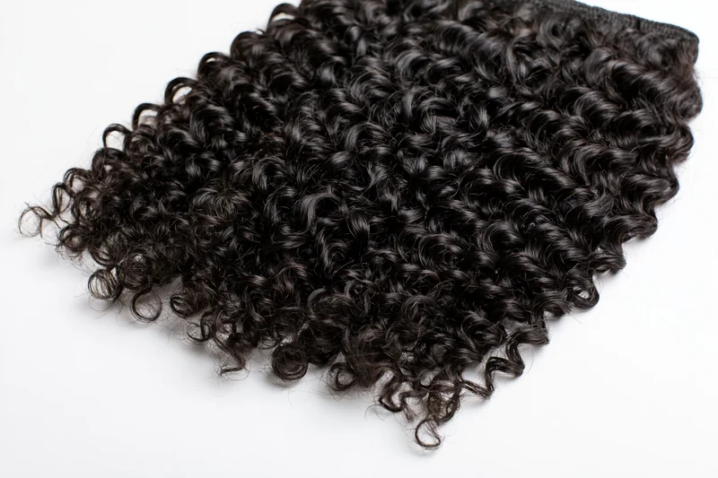 Deep curly black hair extensions laid flat on white background