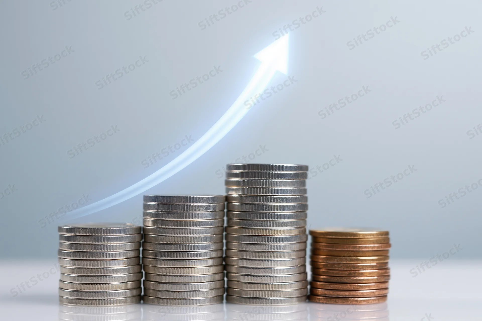 Stacks of coins increasing in height with a glowing arrow rising above them on a light background