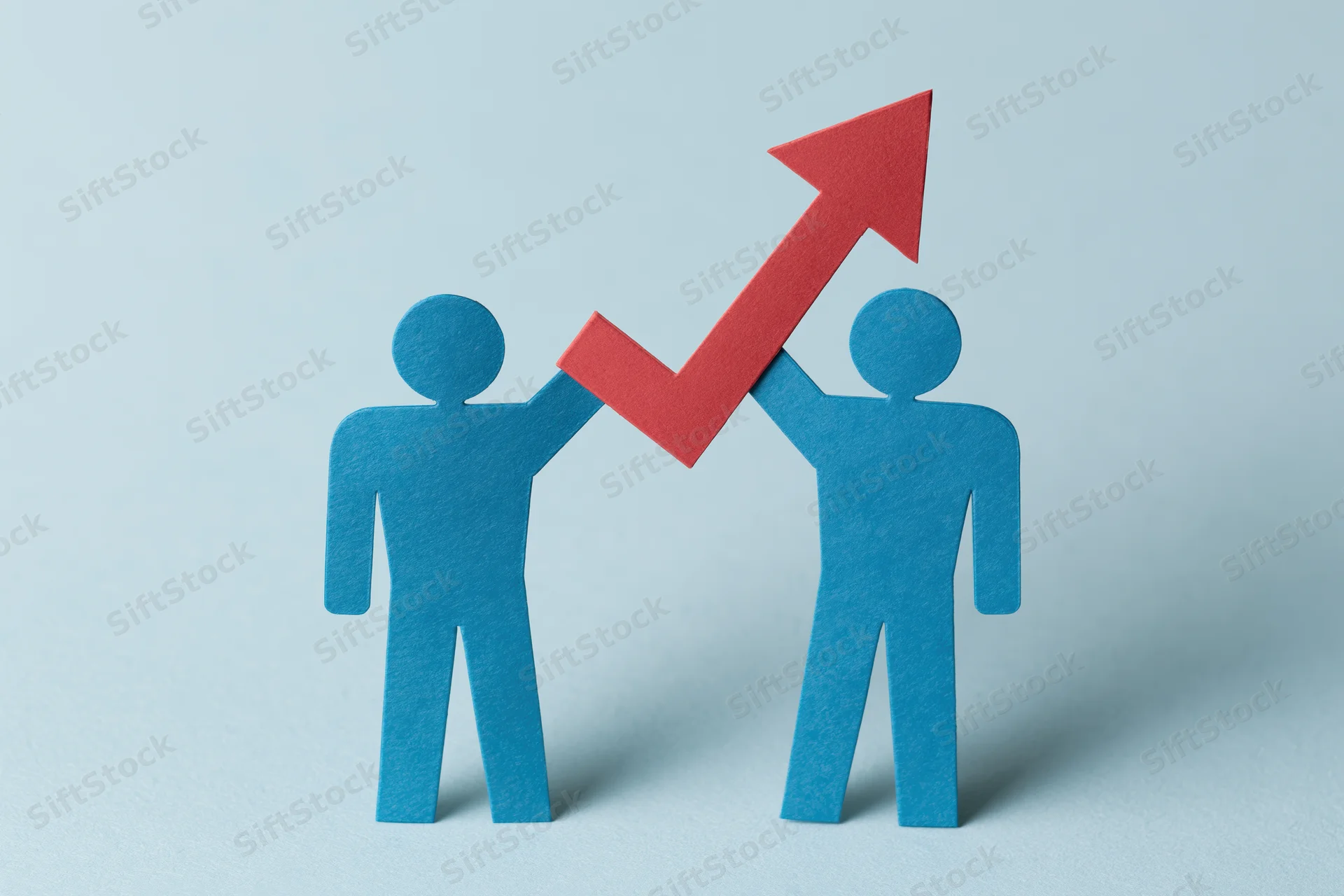 Two blue paper cutout figures holding a red upward arrow against a light blue background
