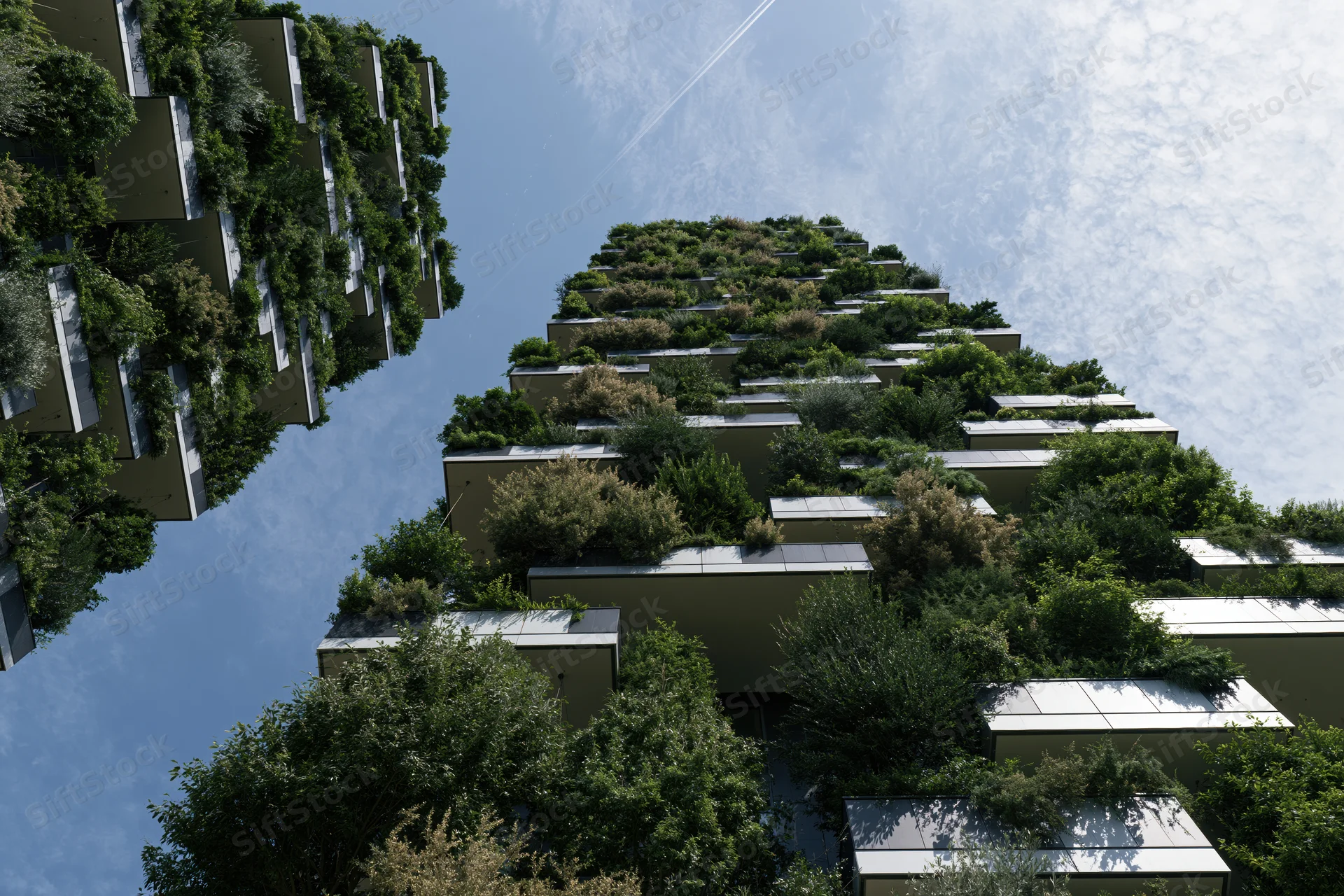 Green-covered residential towers with dense vegetation on terraces and balconies against a blue sky