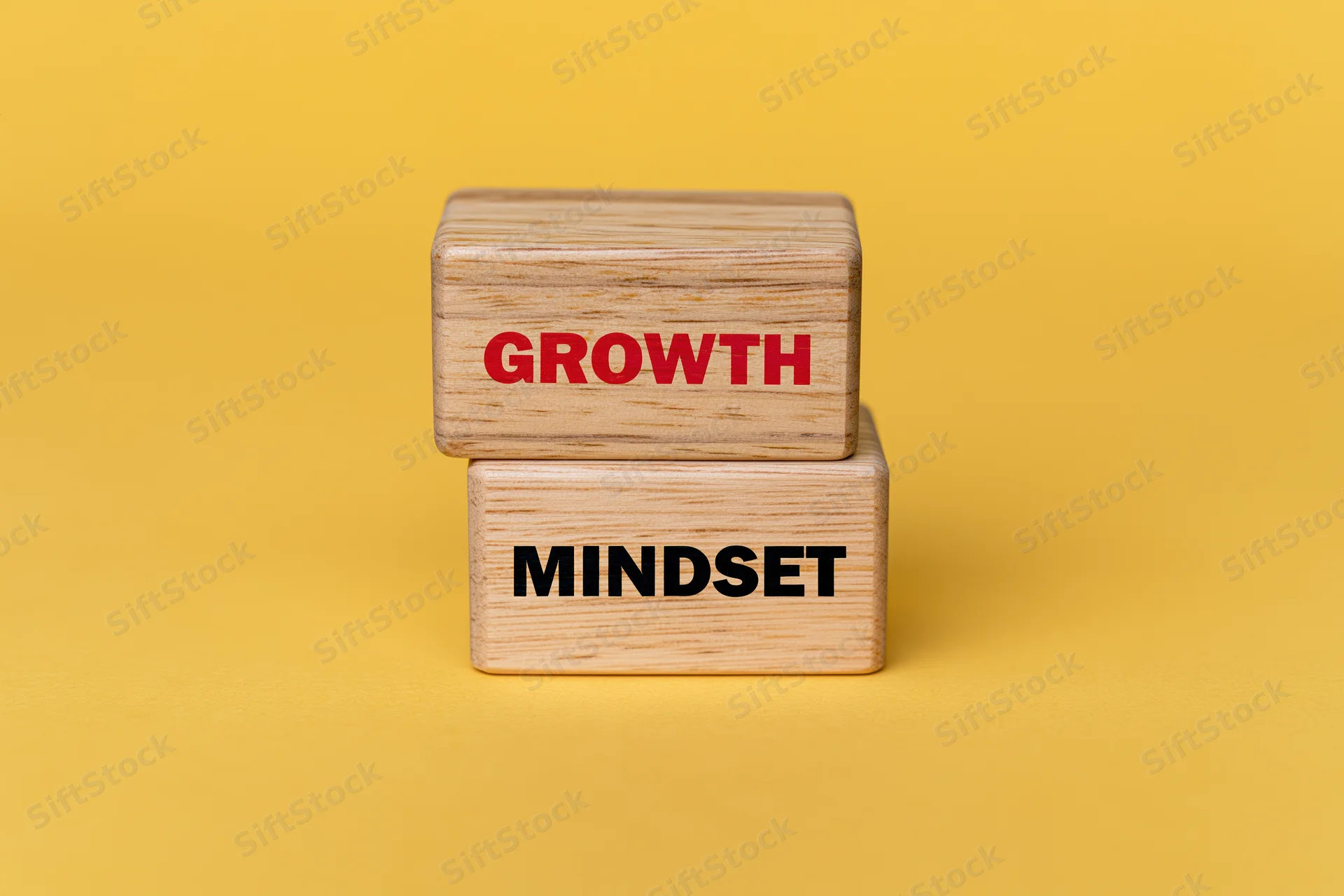 Two wooden blocks stacked offset with growth and mindset text on yellow background