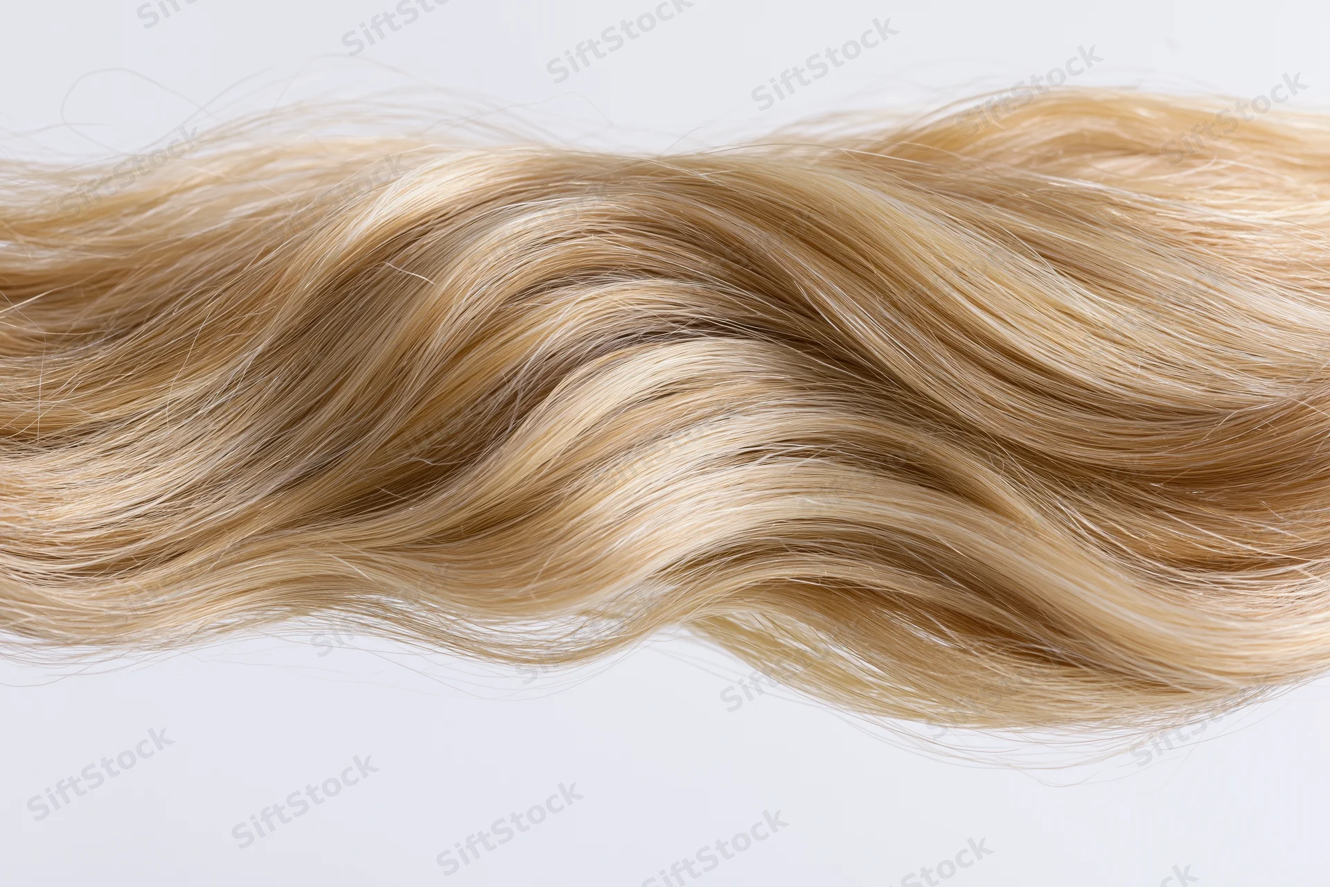 Wavy blonde hair extension floating mid-air against white background