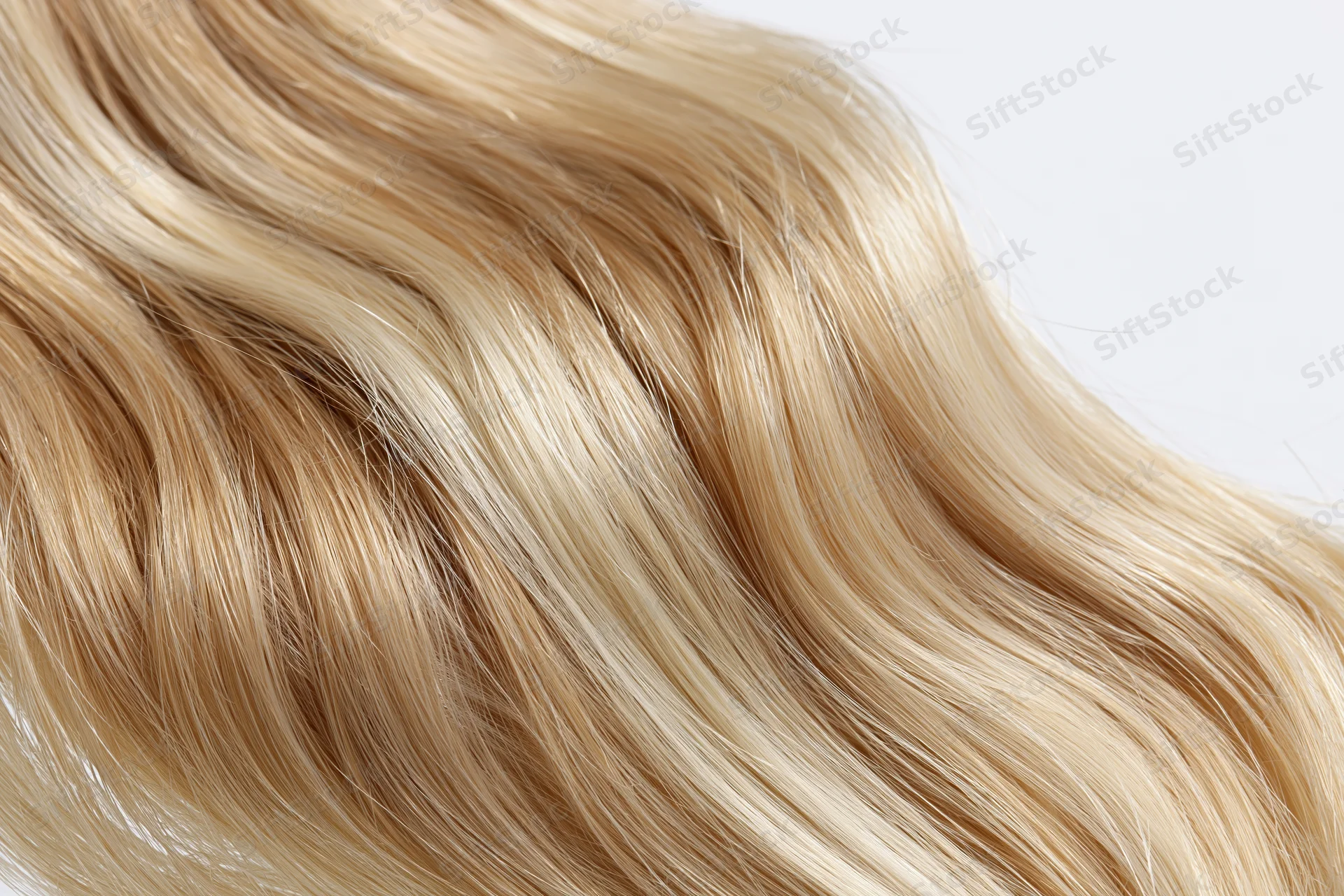 Wavy blonde hair extension floating against white background