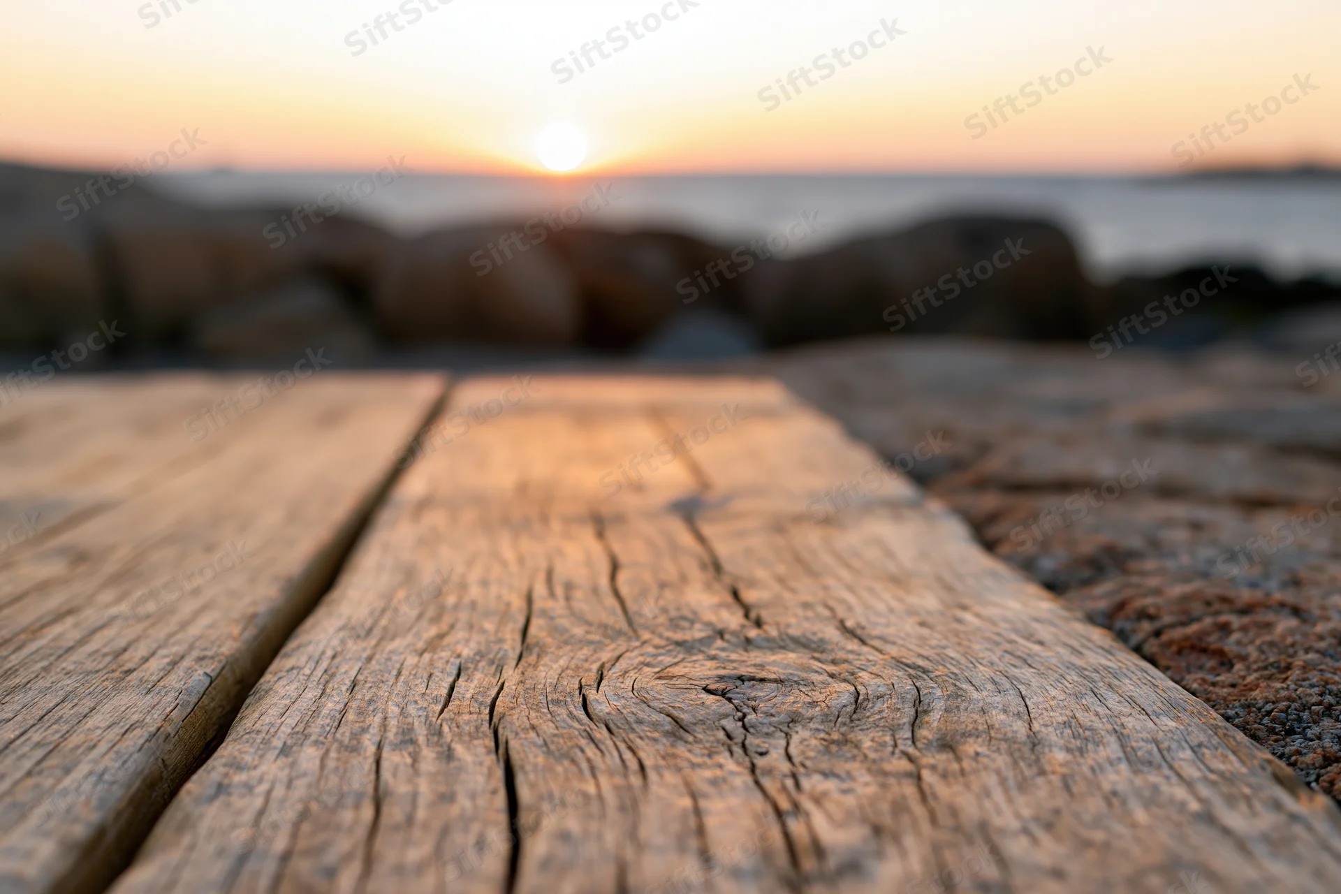 Weathered wooden planks leading toward ocean at sunset from ground level