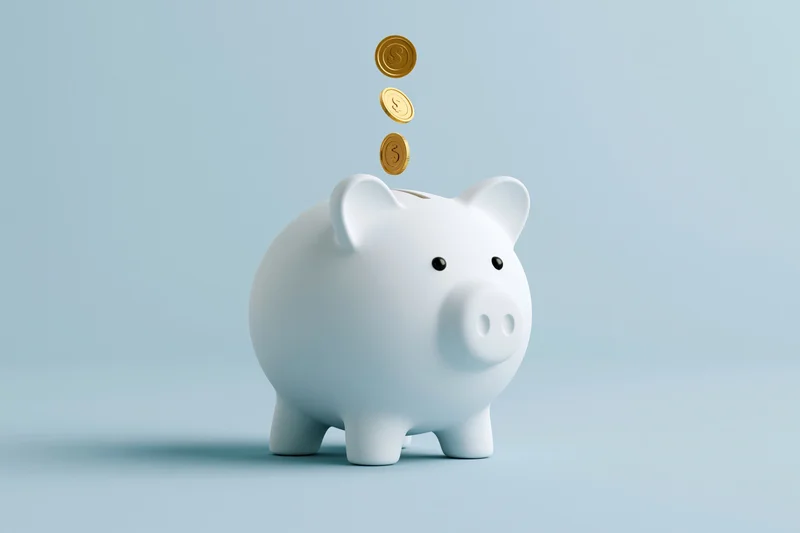 White ceramic piggy bank with gold coins falling into slot on light blue background