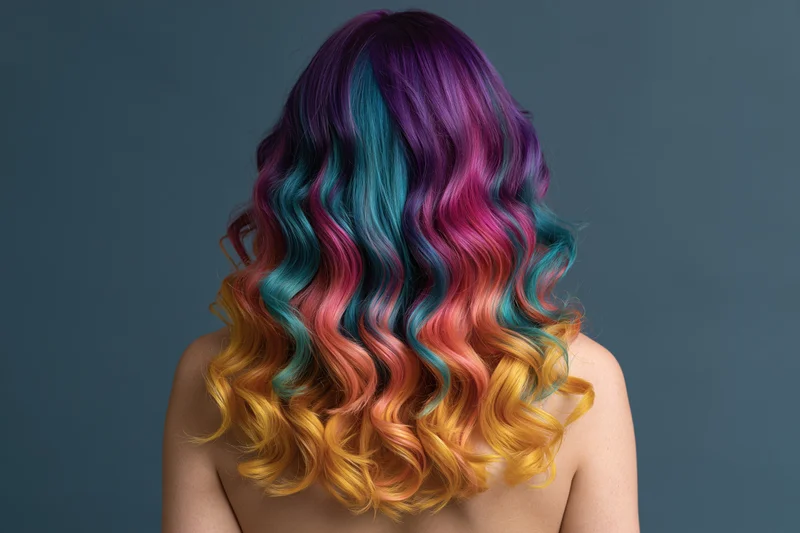 Woman seen from back with long wavy rainbow-dyed hair