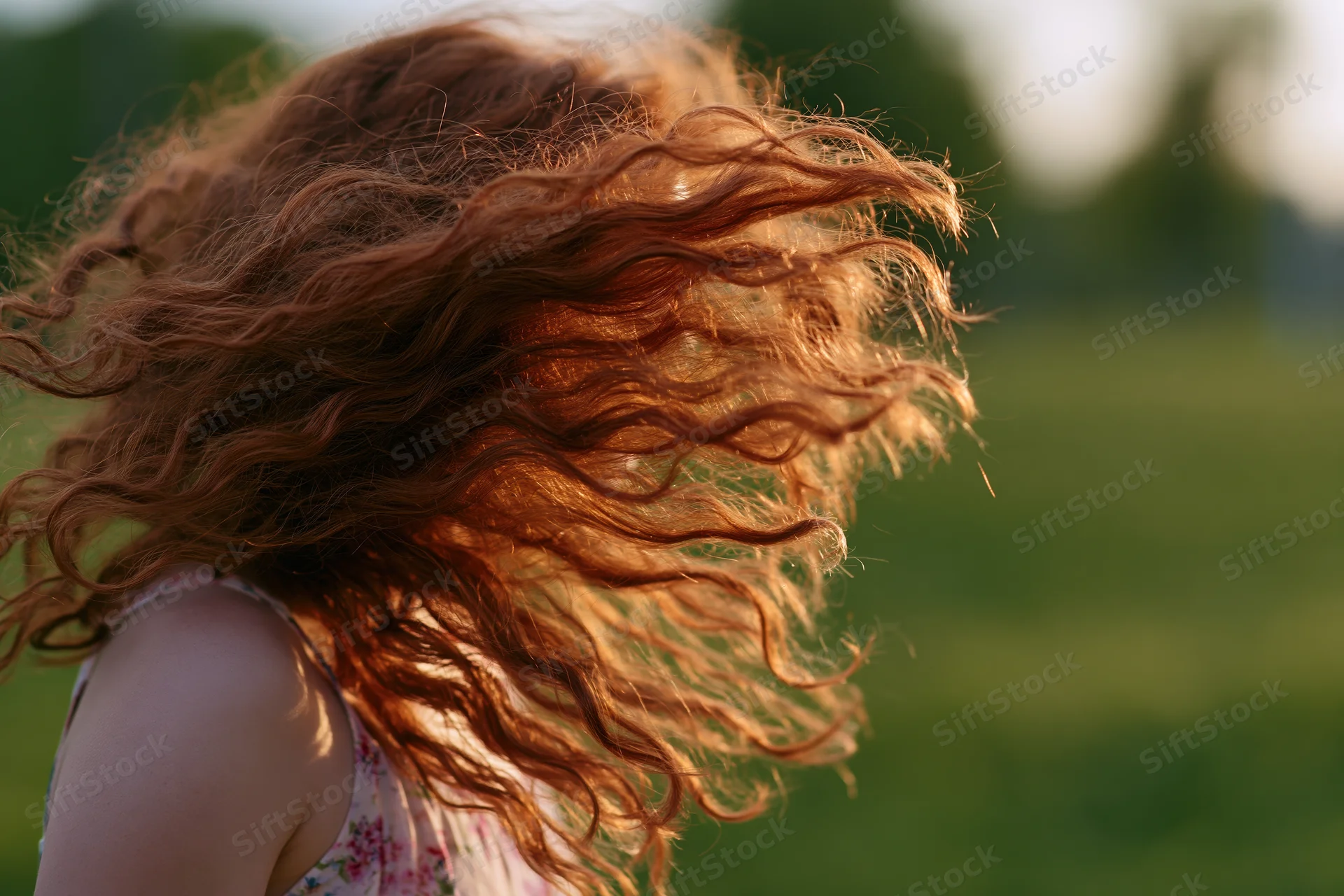 Young girl spinning outdoors with long curly auburn hair flying in the wind