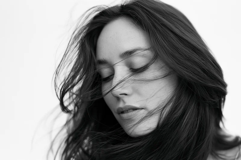 Young woman with long dark hair flowing across her face in a studio portrait