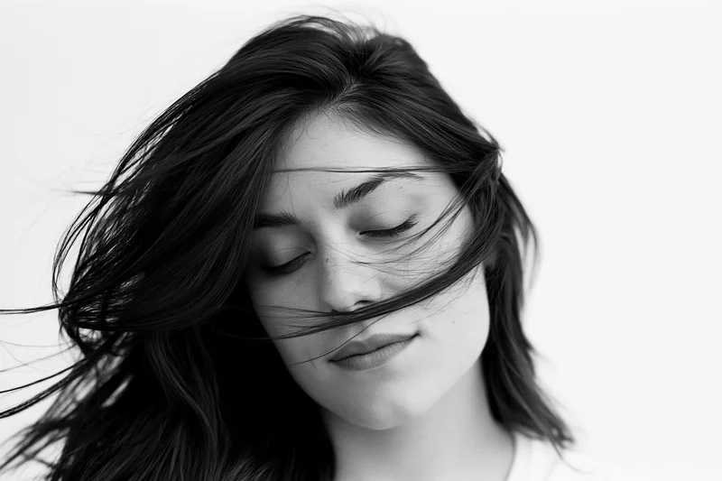 Young woman with long dark hair flowing across her face in a studio portrait