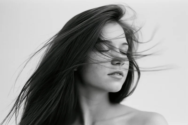 Young woman with long straight hair flowing across her face in a studio portrait