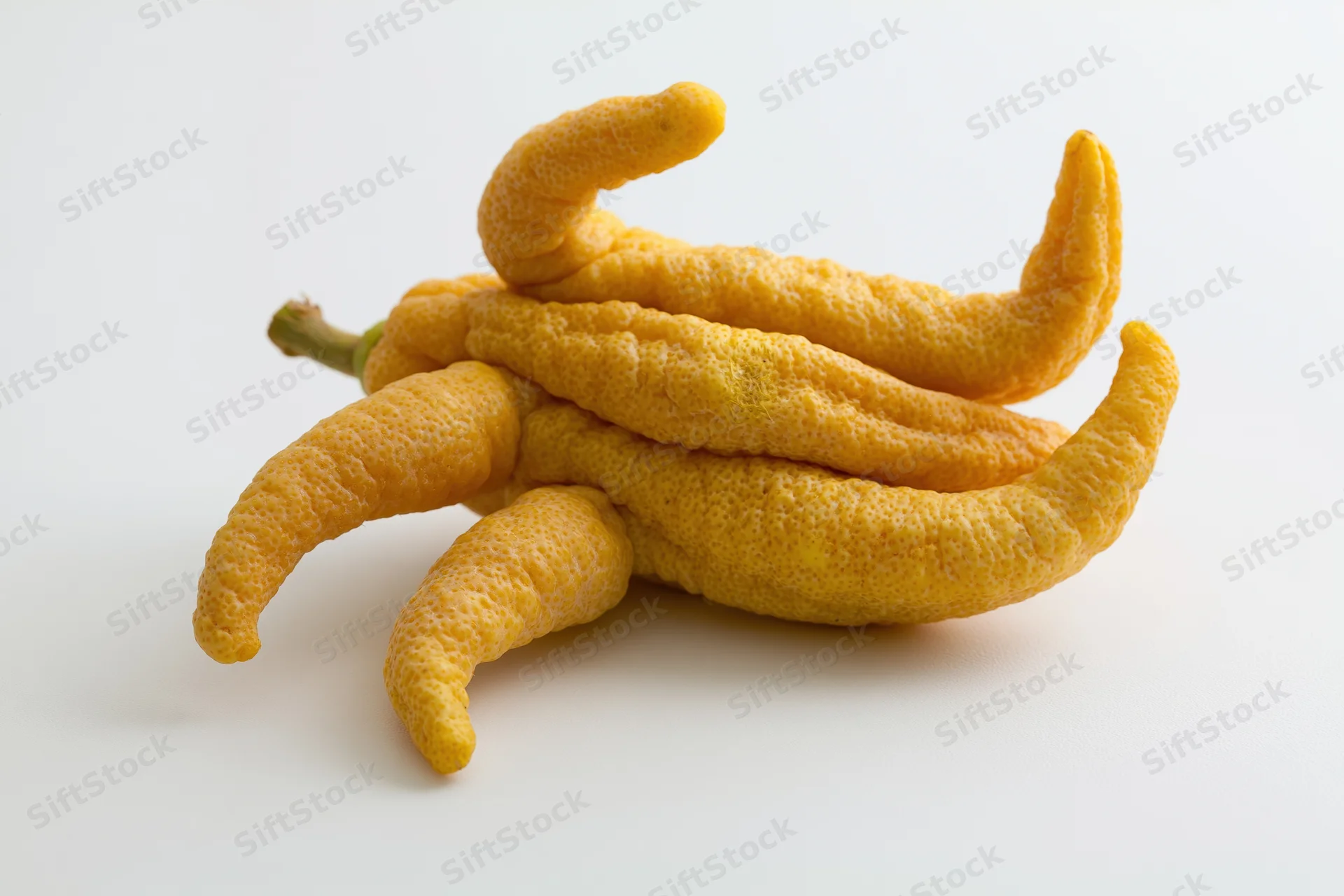 Buddhas hand citron fruit resting on a plain white surface
