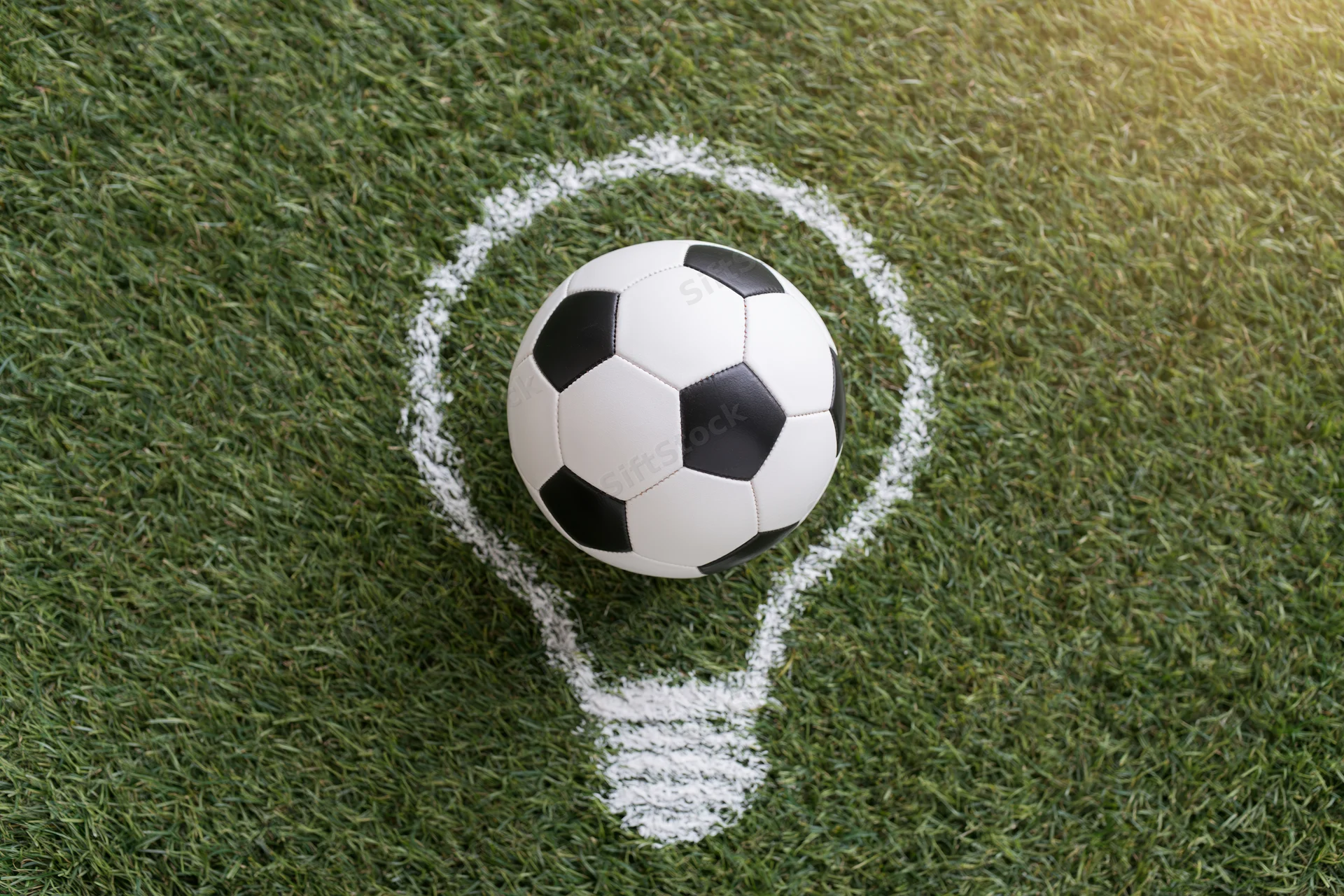 Soccer ball resting on grass within a chalk-drawn lightbulb shape