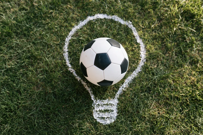 Soccerball resting on grass inside a chalk-drawn lightbulb shape