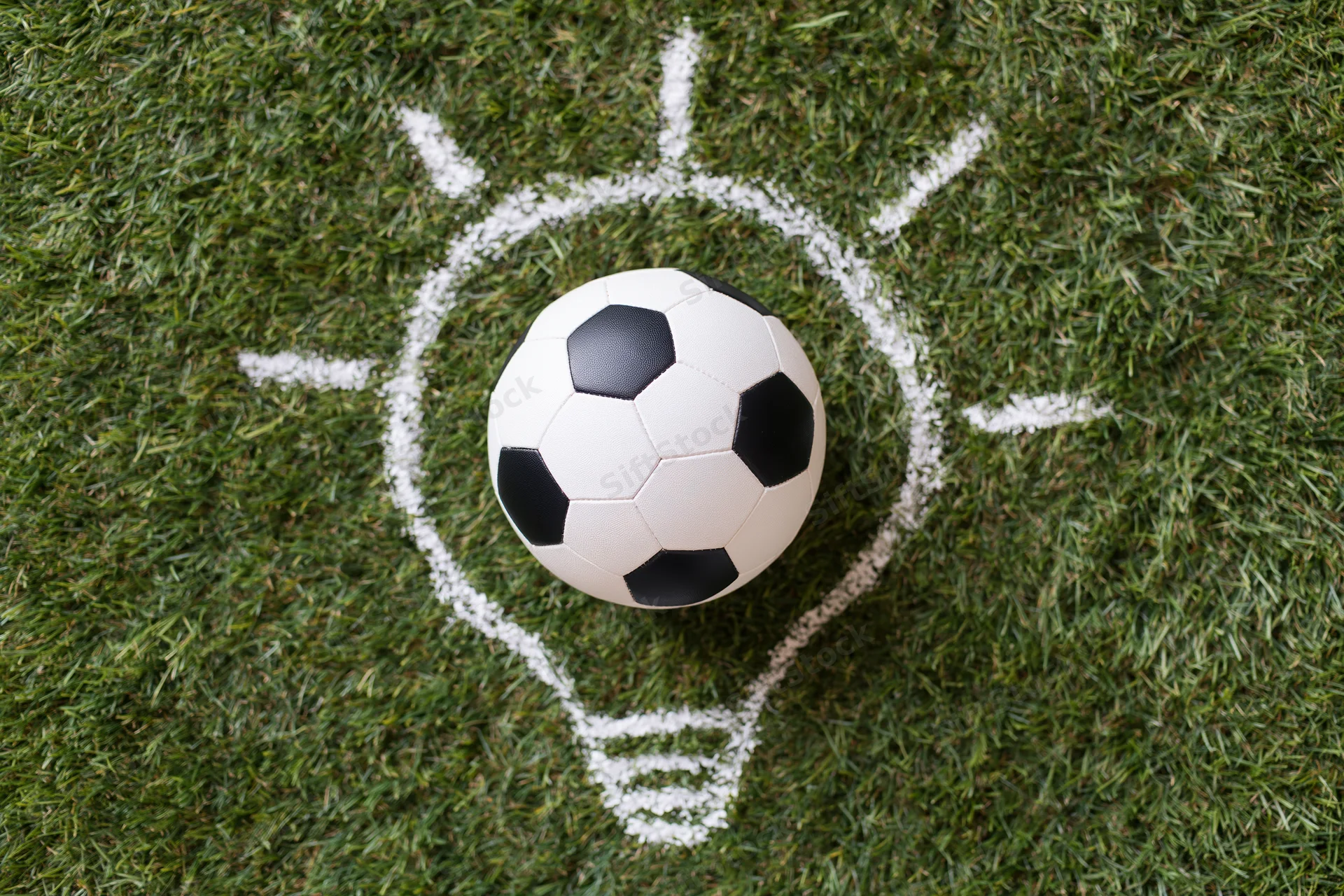 Soccer ball resting on green grass with chalk-drawn lightbulb outline around it