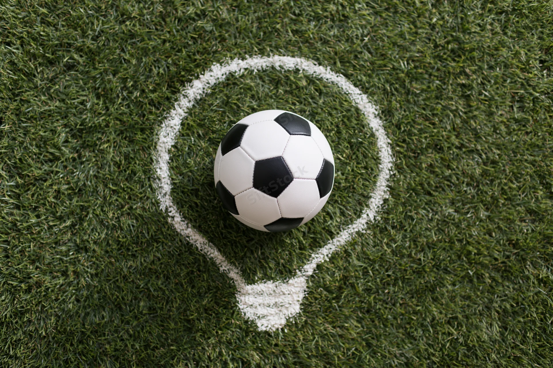 Soccer ball resting on green grass within a white chalk lightbulb outline