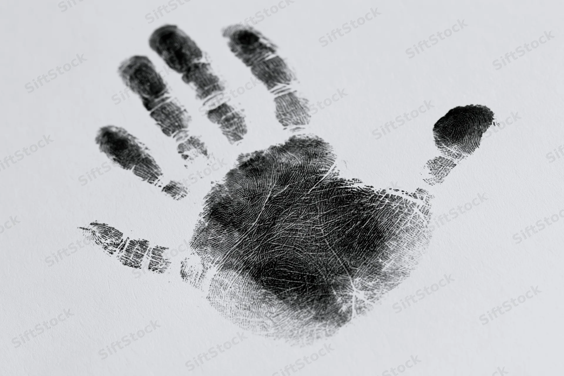 Black ink handprint of a child's right hand on white surface