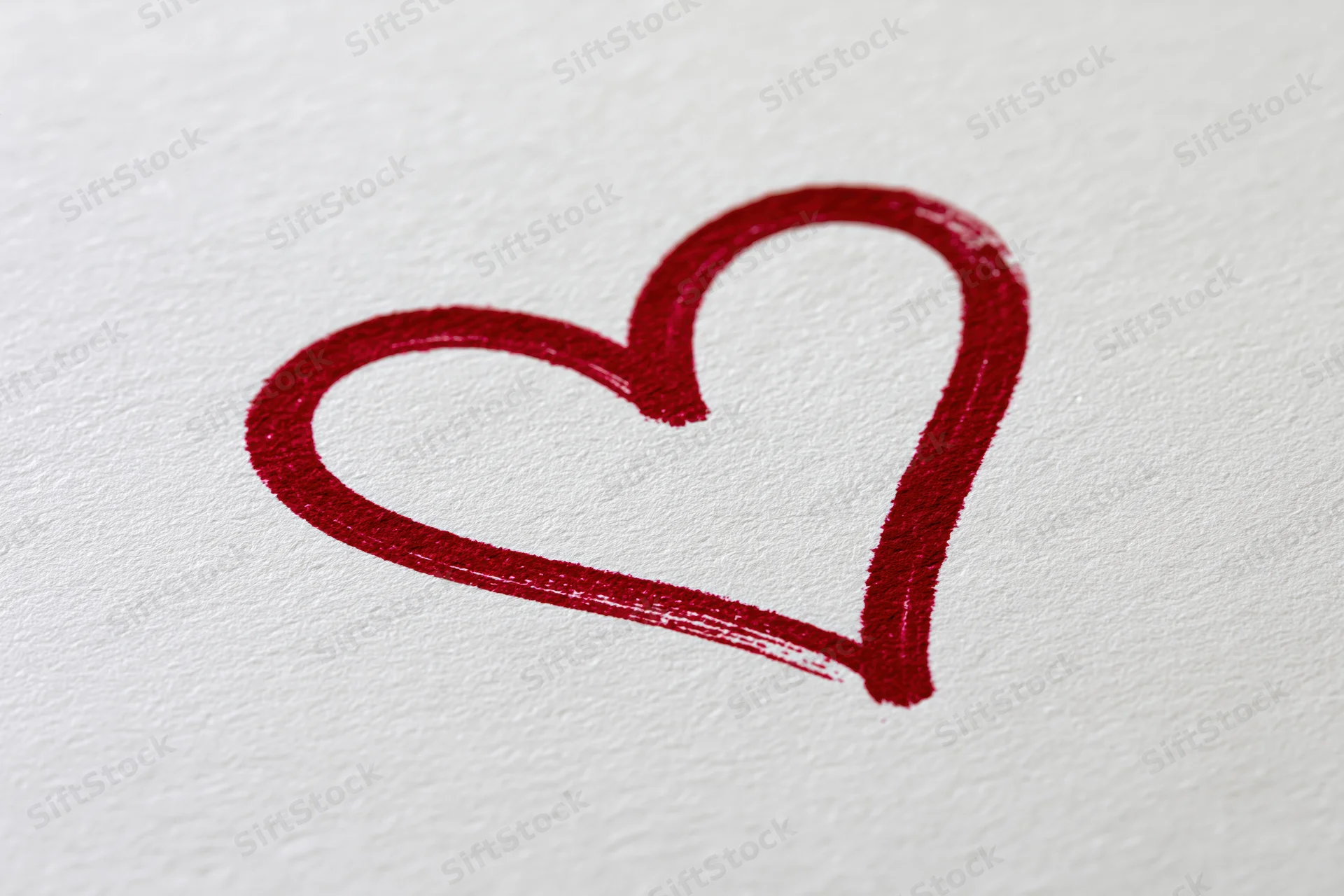 Red heart outline drawn on textured white paper