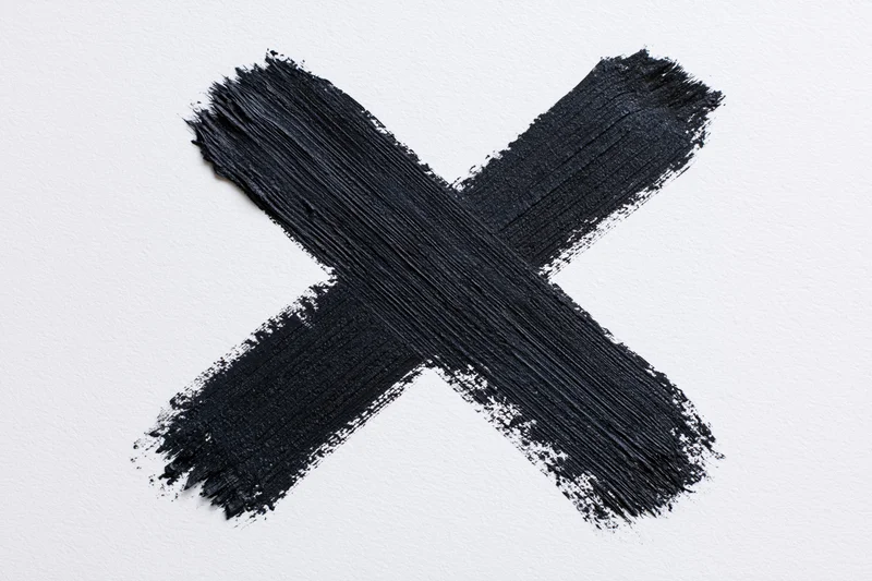 Bold hand-painted black x mark on white surface