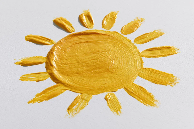 Hand-painted sun drawing on white paper with textured yellow paint strokes
