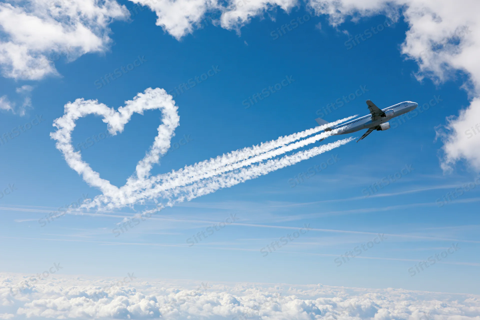 Commercial airplane flying high above clouds leaving a heart-shaped contrail in the sky