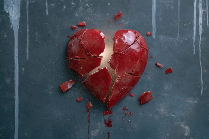 Shattered red ceramic heart on dark textured surface