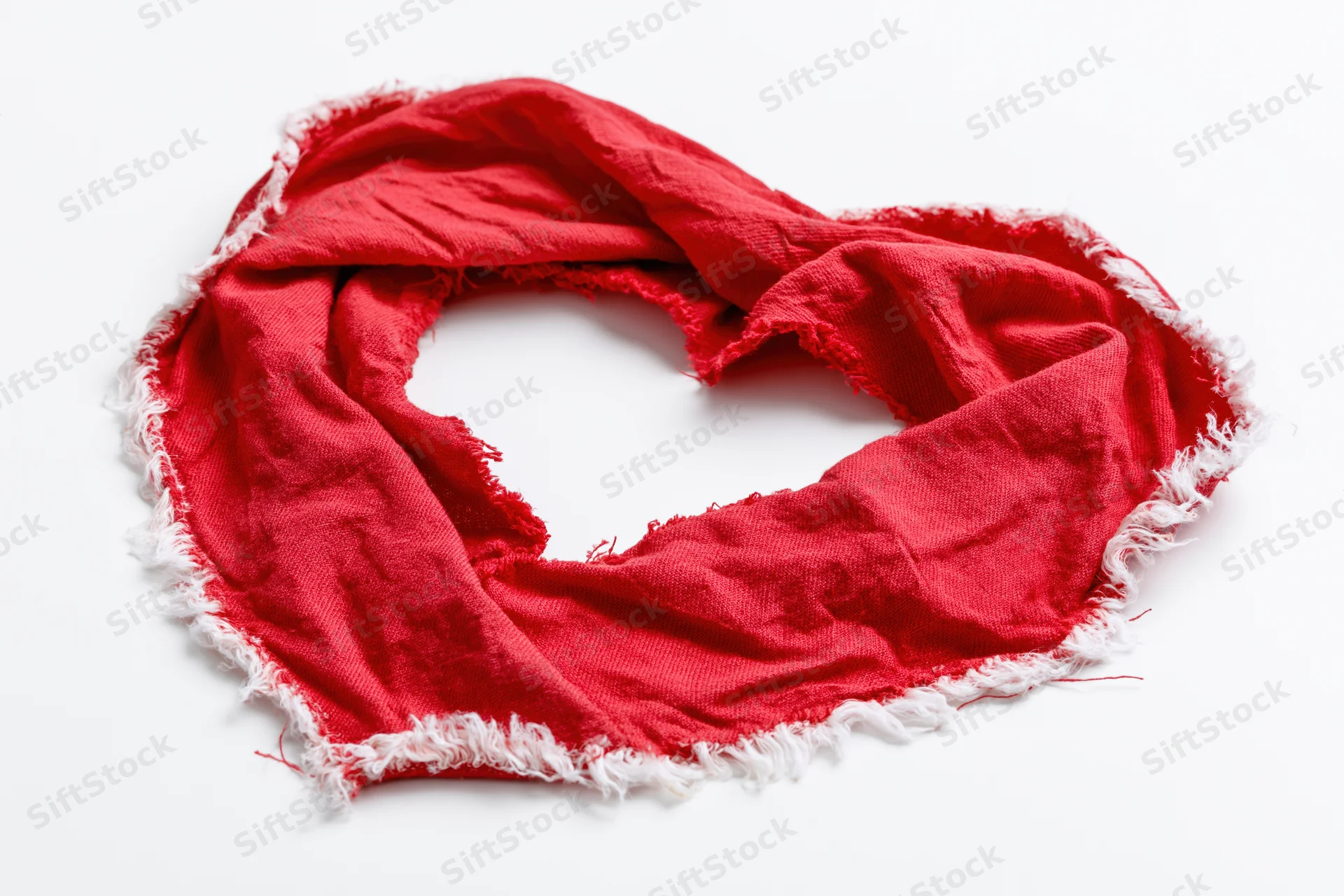 Red torn fabric arranged in heart shape on white background