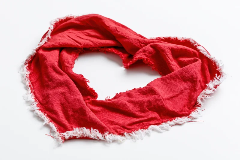 Red torn fabric arranged in heart shape on white background