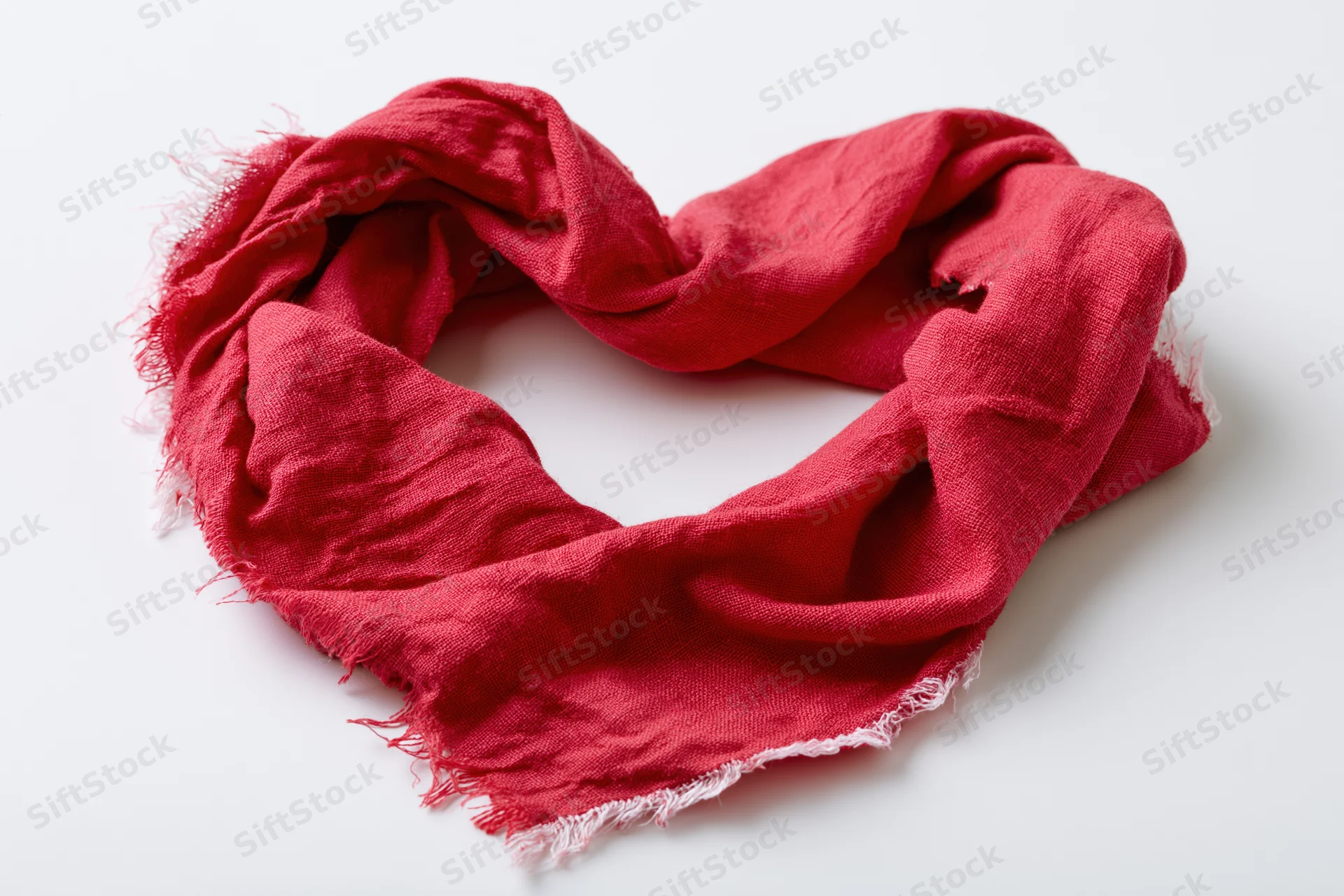 Red scarf arranged in heart shape on white background