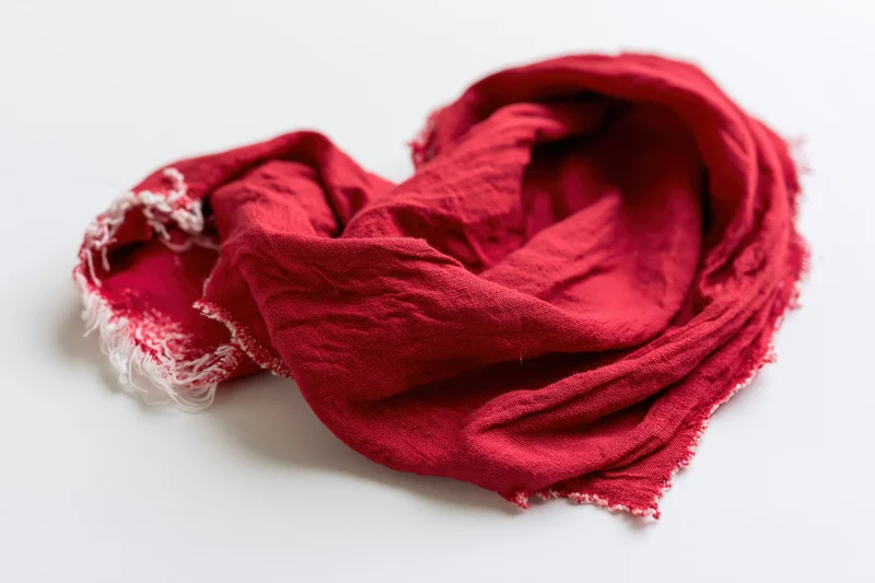 Red scarf crumpled into heart shape on white background