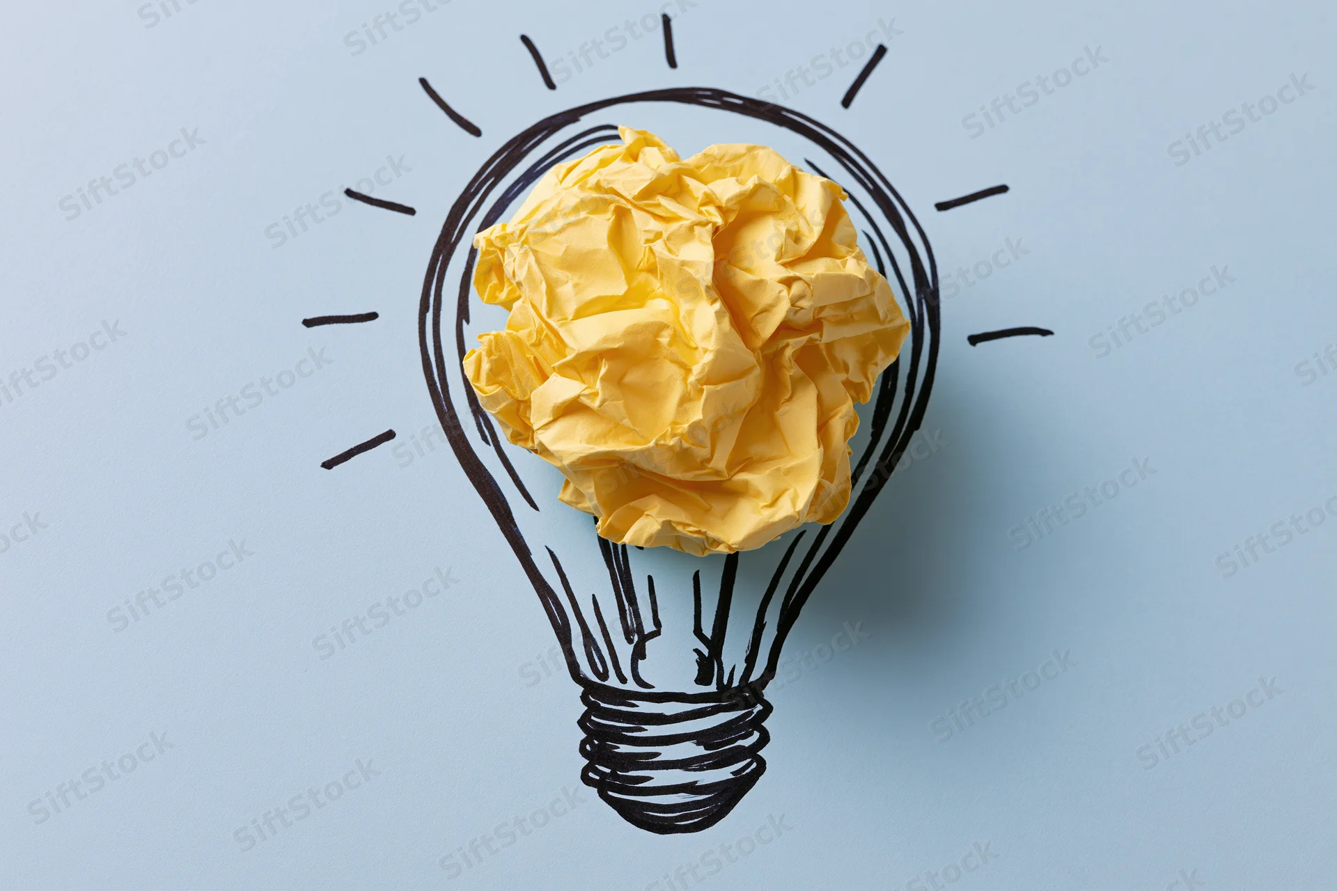 Crumpled yellow paper ball inside hand-drawn lightbulb on blue background