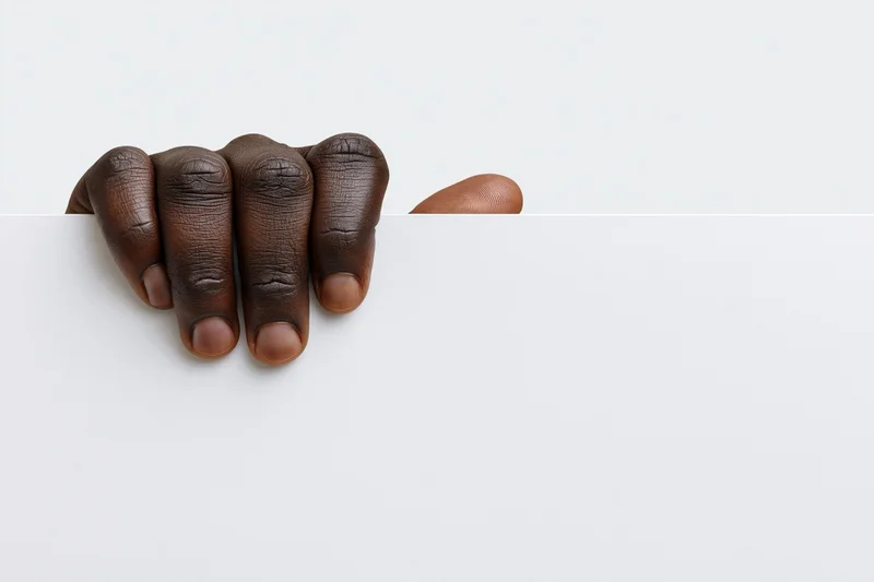 Dark-skinned hand gripping top edge of blank white paper with copyspace below