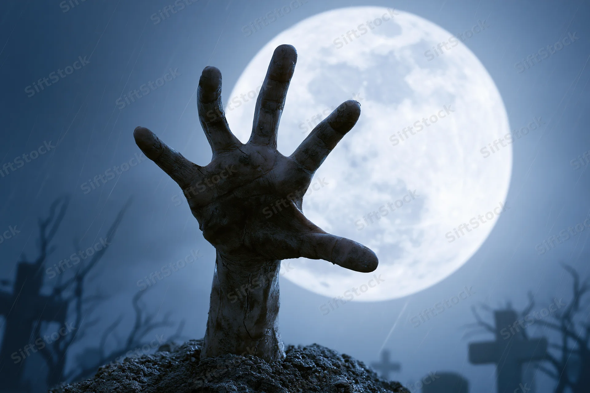 Decayed hand emerging from soil in a graveyard under a full moon at night