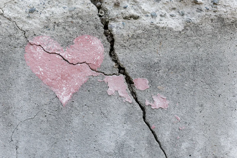 Broken pink heart painted on cracked concrete surface