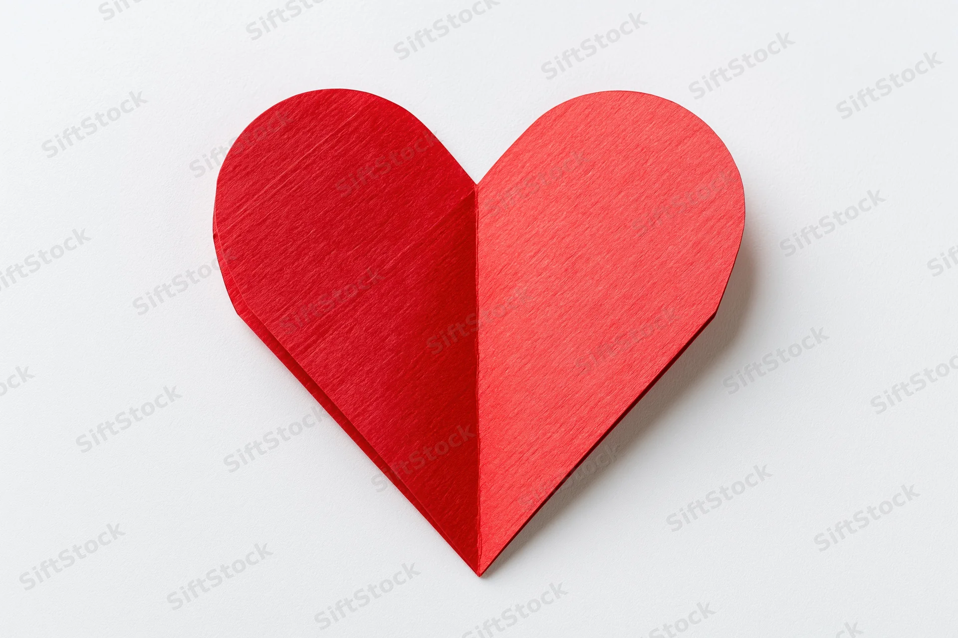 Folded red paper heart centered on plain white background
