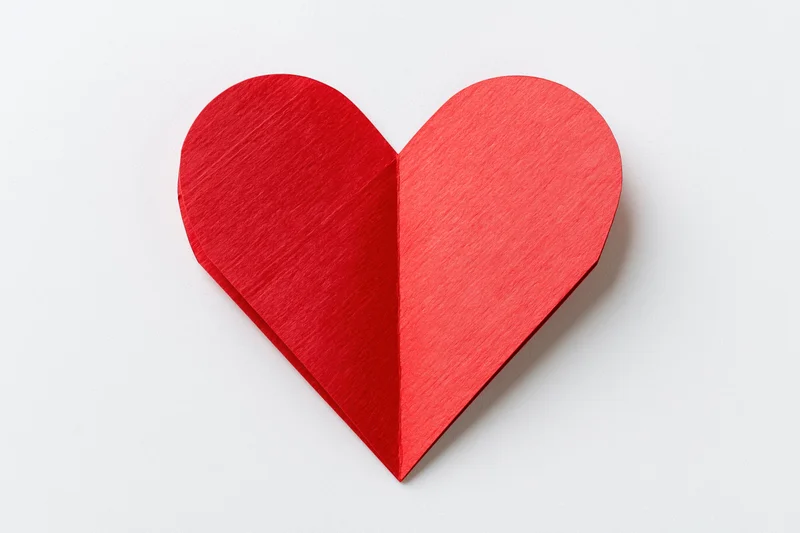 Folded red paper heart centered on plain white background
