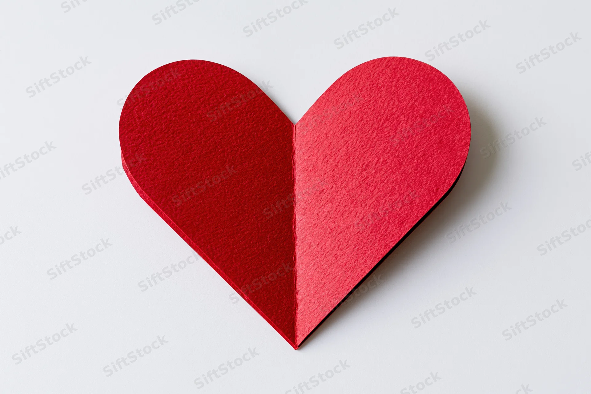 Folded red paper heart centered on white background