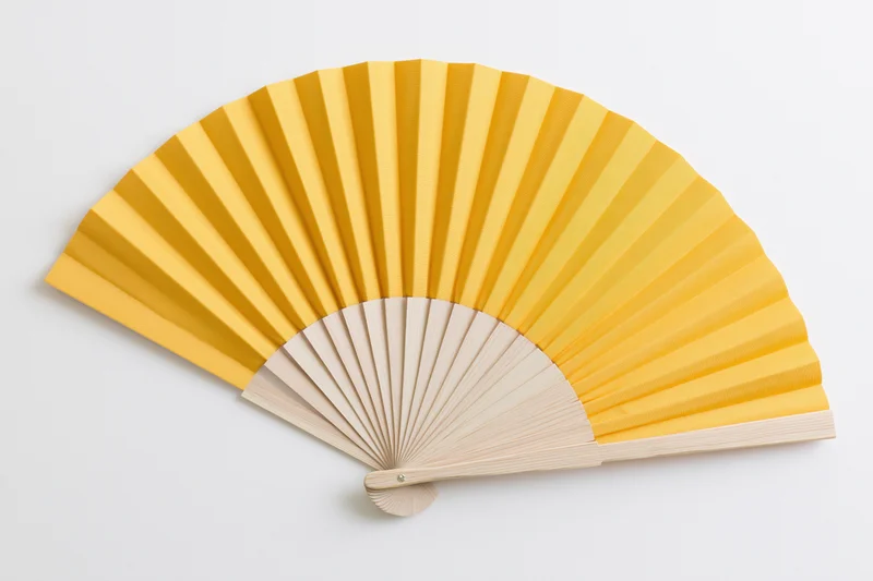 Fully opened yellow folding hand fan with bamboo ribs on white background