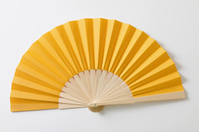 Fully opened yellow folding hand fan with wooden handle on white background