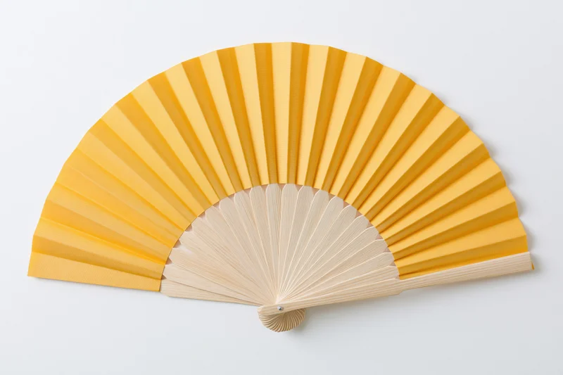 Fully opened yellow folding hand fan with wooden ribs on white background