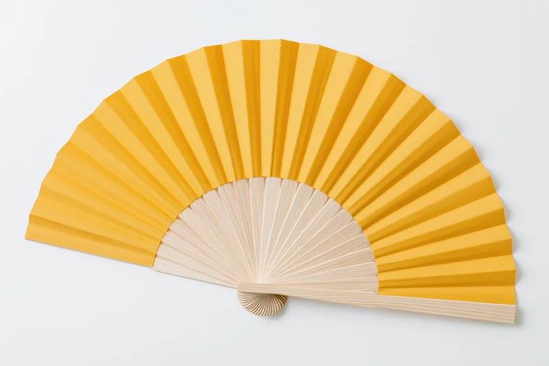 Fully opened traditional folding hand fan with plain yellow paper and wooden ribs on white background
