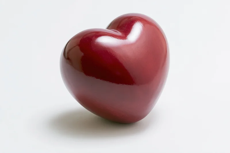 Glossy red heart-shaped object centered on white background with copyspace
