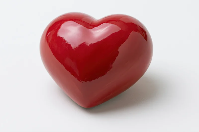 Glossy red ceramic heart object centered on white background