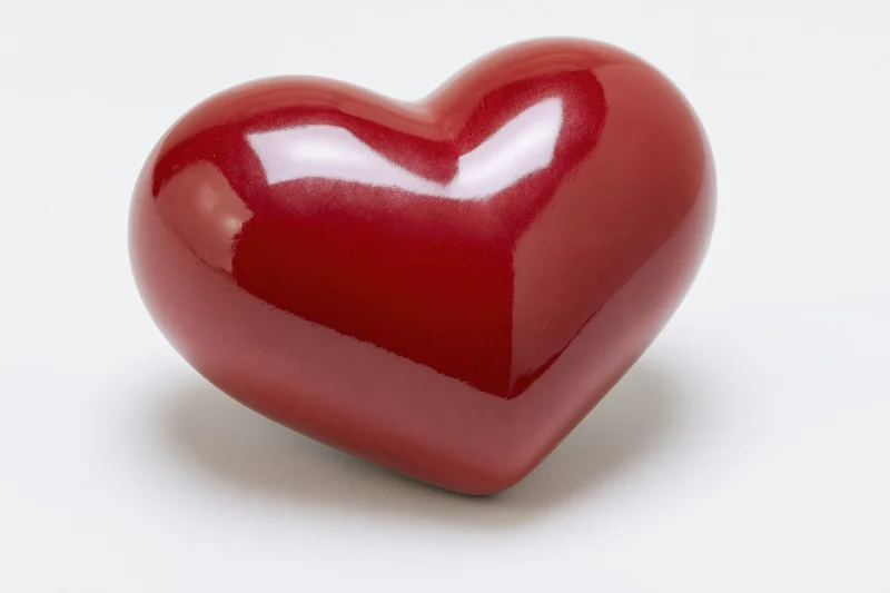 Glossy red ceramic heart object isolated on white background