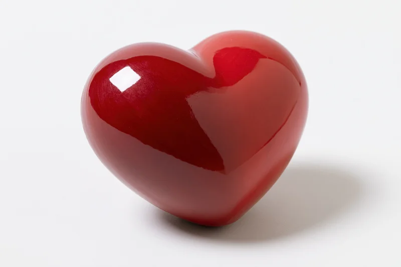 Glossy red heart-shaped object centered on white background