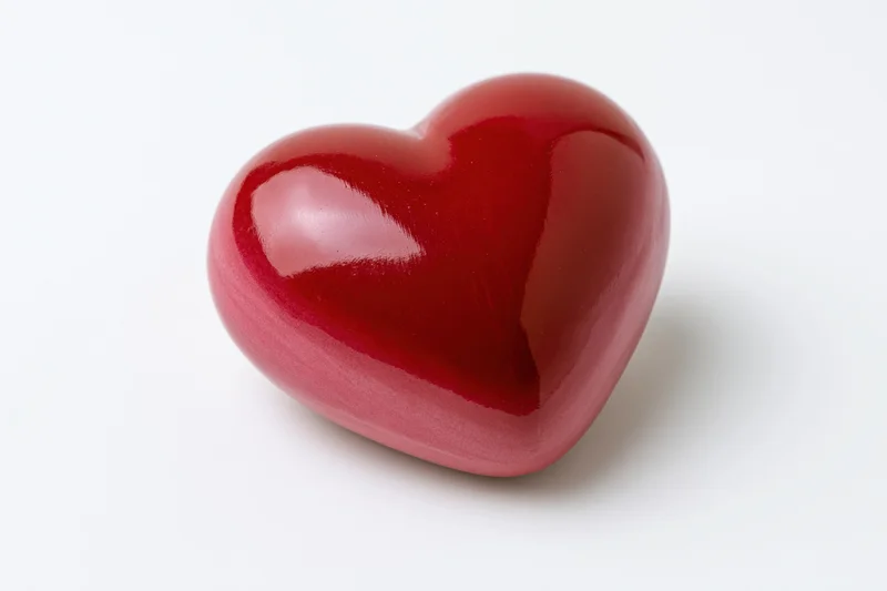 Glossy red heart-shaped object centered on pure white background