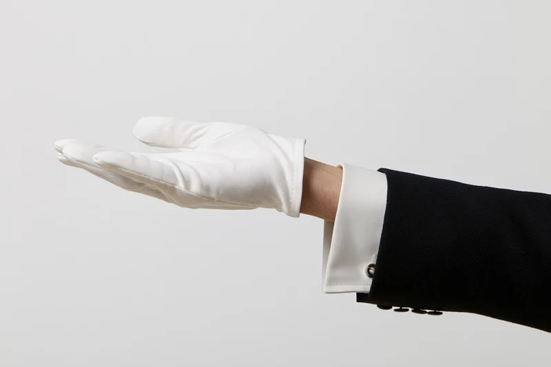 Gloved hand extended palm-up in offering gesture against plain background