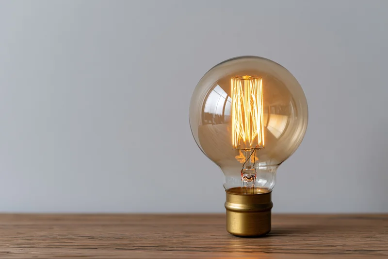 Glowing edison filament lightbulb on wooden table with copyspace