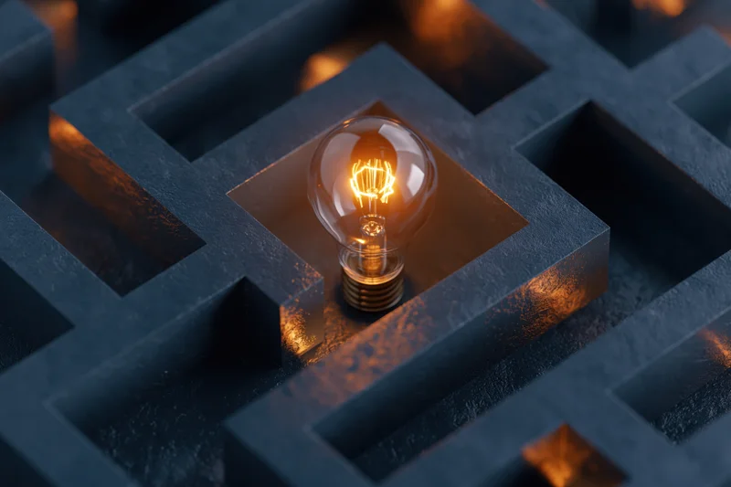 Glowing lightbulb at center of dark maze structure