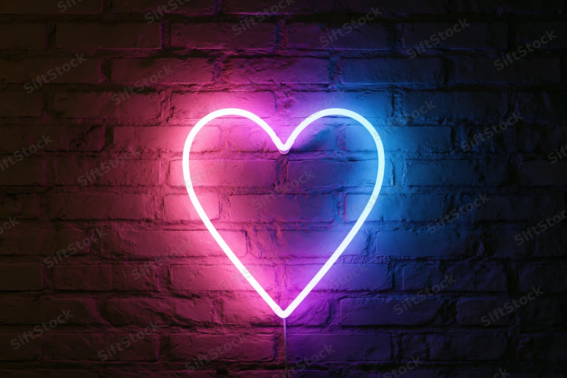 Glowing neon heart sign mounted on dark brick wall with pink and blue gradient light